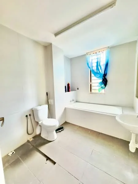 Bathroom features: white toilet, bathtub, sink with pedestal, window with sheer blue curtain, grey tile flooring, white painted walls, ceiling light fixture, exposed plumbing.