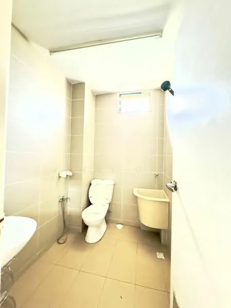 Bathroom features: white toilet, handheld shower, wall-mounted faucet, sink with pedestal, grey tiled walls, beige tiled flooring, small window for natural light, light fixture on ceiling.