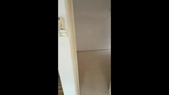 Room features: plain white walls, light-colored tiled flooring, door frame, light switch, no visible furniture or decor; style: minimalist.