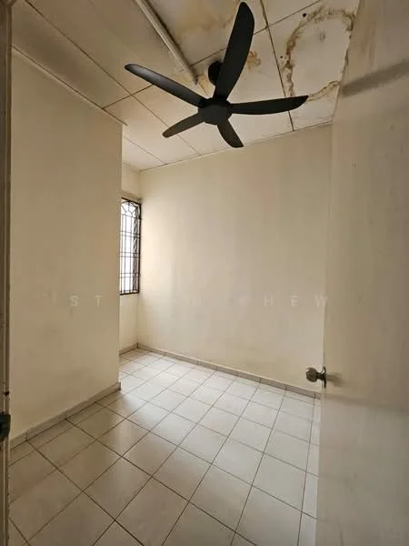 Room features: white painted walls, ceiling fan, square tile flooring, window with metal grille, neutral colour scheme, corner room, no visible furniture, natural light from window.