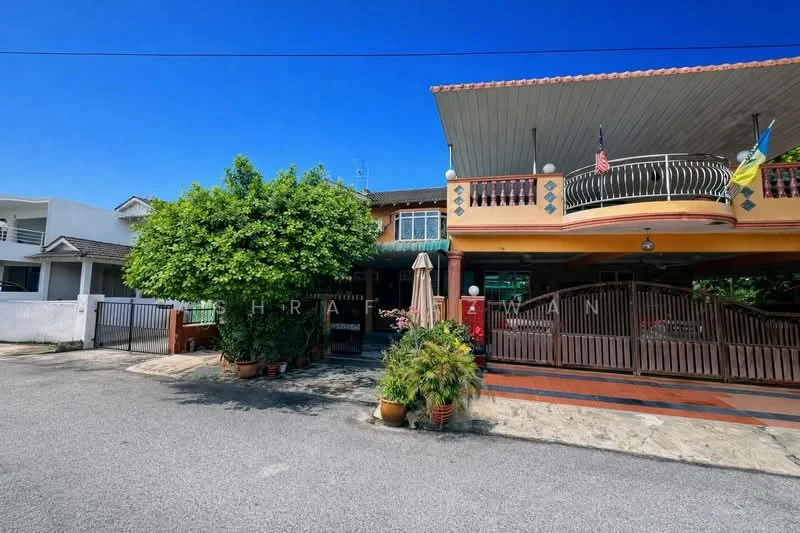 Exterior type: semi-detached house; features: two-storey structure, cream painted facade, recessed balconies, paved driveway, manicured garden with shrubs, umbrella over outdoor seating area, visible flagpoles with flags, decorative railing on balcony, tile roof, outdoor plants in pots; style: traditional.