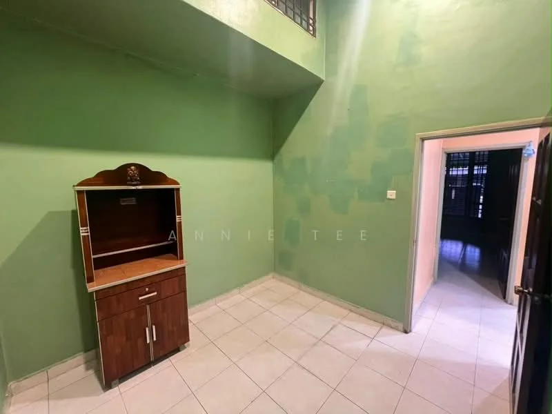 Room features: green painted walls, white tiled flooring, wooden cabinet with open shelving, high ceiling, doorway leading to another room, window with security bars.