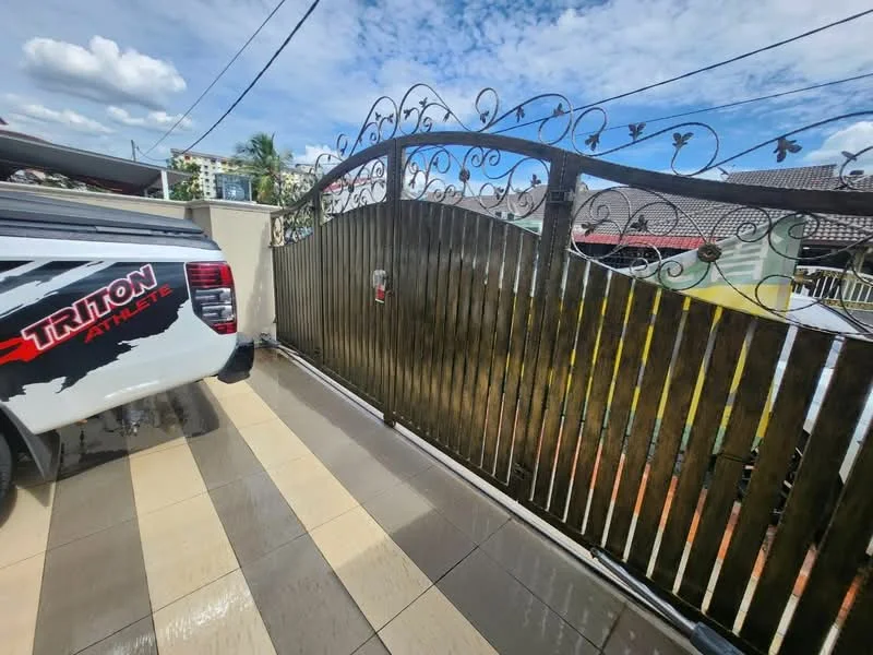 Exterior features: metal gate with decorative design, paved driveway, grey and beige tiled flooring, surrounding residential buildings, clear blue sky, greenery in background; style: modern.