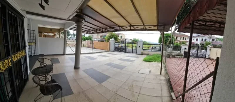 Exterior features: covered patio area, stone-paved flooring, metal gate, fenced perimeter, manicured lawn, outdoor seating with chairs, adjacent residential buildings, partial view of driveway.