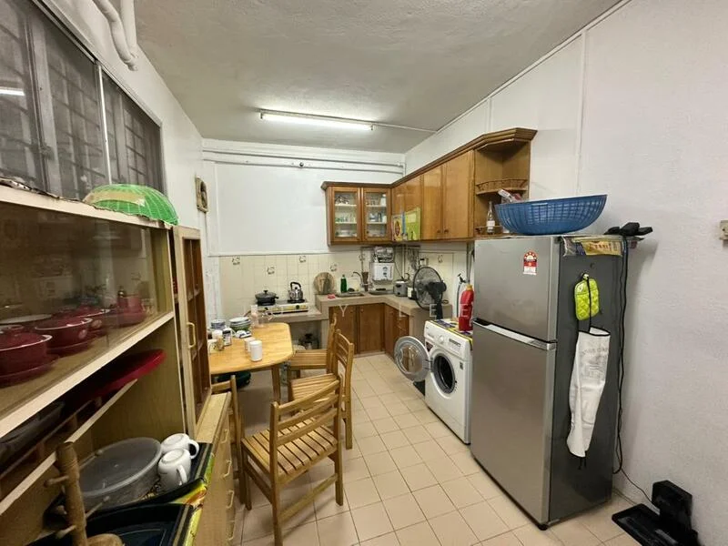 Kitchen features: wood cabinetry, white tiled walls, ceramic tile flooring, stainless-steel fridge, built-in oven, freestanding washing machine, kitchen table with wooden chairs, countertop with sink, kettle, coffee machine, various kitchen utensils, open shelving, window with metal grille.