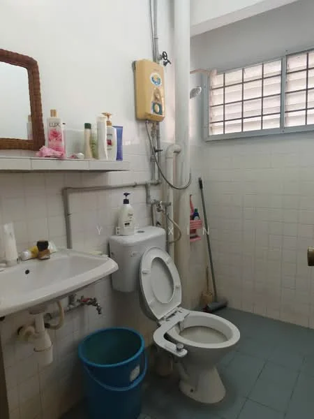 Bathroom features: white tiled walls, light blue tiled flooring, single-sink vanity, wall-mounted mirror, toilet, shower with wall-mounted water heater, window with metal grille, plastic bucket.
