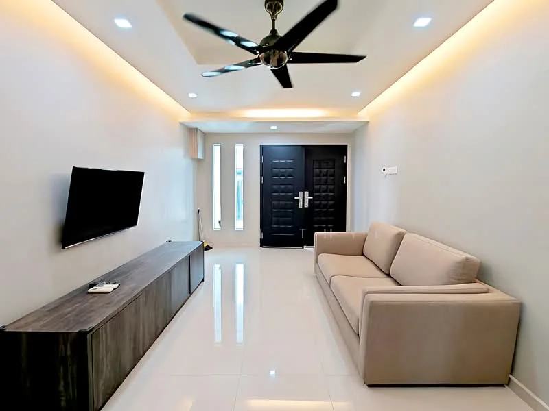 Living features: light grey painted walls, white ceiling with recessed downlights, 5-blade ceiling fan with light, large flat-screen TV mounted on wall, dark wood TV console, cream fabric sofa, glossy white tile flooring, double-door main entrance, decorative wall with vertical panels; style: modern.