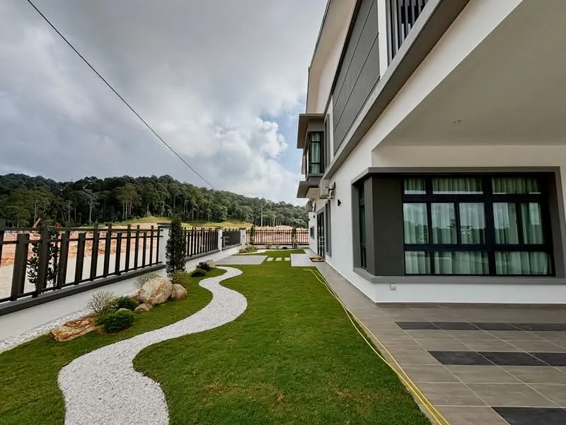 Exterior type: detached bungalow; features: manicured lawn, stone-paved walkway, decorative rocks, landscaped garden, fence with vertical slats, multiple trees in background, grey painted facade, large windows with green curtains, outdoor lighting fixtures, modern architectural design; style: modern.