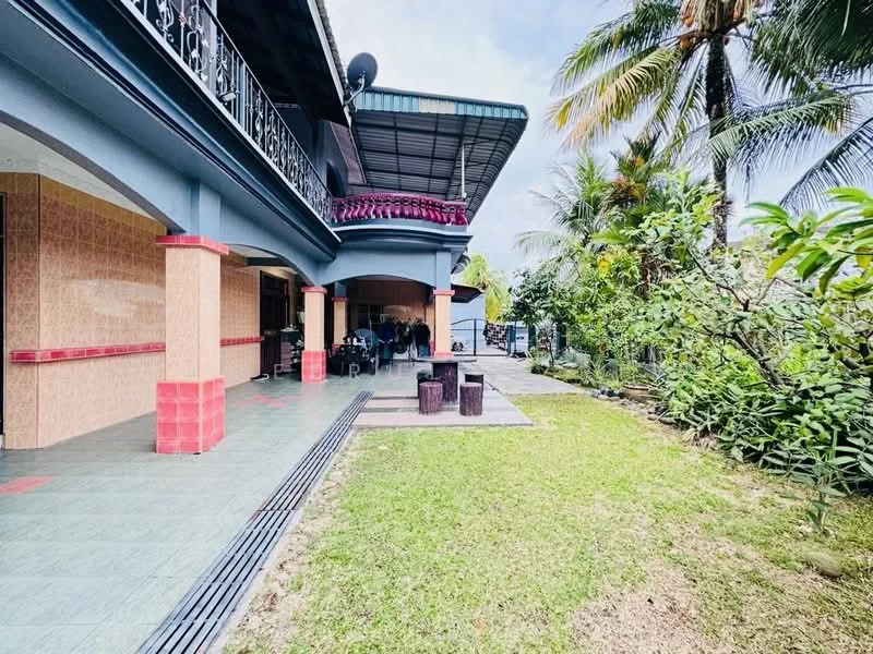 Exterior type: detached bungalow; features: manicured lawn, tropical landscaping, paved walkway, covered patio area, balcony with wrought iron railing, exposed concrete facade, red accent columns, outdoor seating area, surrounded by palm trees, garden area; style: tropical-modern.