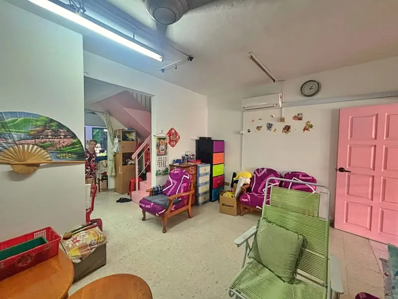 Living features: light-colored flooring, white painted walls, exposed ceiling with ductwork, wall-mounted air conditioning unit, clock on the wall, colorful storage cabinet, two purple armchairs, wooden dining table, green folding chair, decorative wall art, fan, boxes stacked in the corner; style: modern.