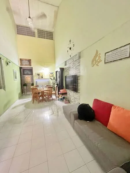 Living features: green painted walls, white tiled flooring, high ceiling, ceiling fan, wall-mounted TV, sofa with orange and red cushions, decorative wall clock, stone feature wall, dining table with chairs, open layout to dining area; style: modern.