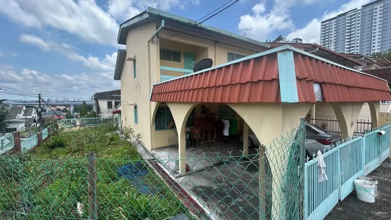 Exterior type: detached bungalow; features: red pitched tile roof, cream painted facade, arched porch with columns, manicured lawn, surrounded by greenery, fenced perimeter, driveway with parking space, satellite dish on roof, adjacent to residential area, city skyline view in background; style: traditional.