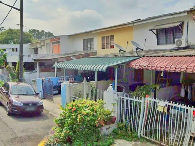 Exterior type: linked terrace house; features: red tiled roof, white painted facade, green awning over porch, satellite dishes on roof, fenced front yard, manicured garden with flowering plants, driveway with parked car, multiple windows with grilles, outdoor seating area, street view with surrounding greenery; style: traditional.