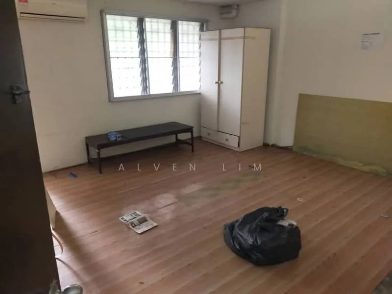 Room features: wooden flooring, white painted walls, window with metal grilles, air conditioning unit on wall, built-in wardrobe, dark wooden bench, scattered papers on floor, black garbage bag.