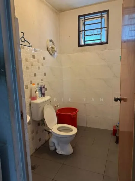 Bathroom features: white toilet, wall-mounted sink, grey floor tiles, white wall tiles with marble pattern, decorative wall tiles, window for natural light, red plastic bucket, wall-mounted soap holder, hanging hook, shower area.