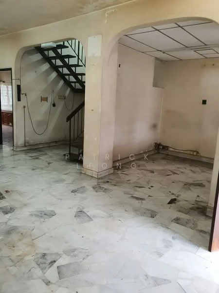 Room features: marble flooring, white painted walls, staircase with wooden railing, ceiling with grid tiles, wall-mounted electrical outlets, corner with plumbing visible, open layout, natural light from windows.