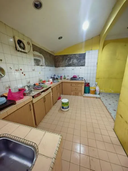Kitchen features: single-bowl stainless-steel sink, wall-mounted faucet, laminate countertop, wood cabinetry, tile backsplash, ceramic tile flooring, exposed brick wall, recessed ceiling lights, open layout, yellow painted walls, multiple storage containers, cleaning supplies visible.