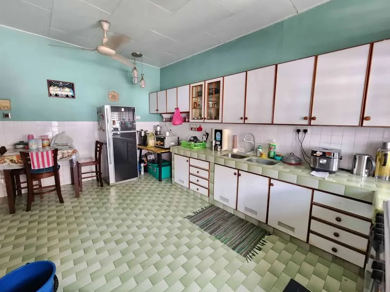 Kitchen features: green painted walls, white cabinetry with wooden trim, green countertop, double-bowl stainless-steel sink, chrome pull-down faucet, built-in oven, freestanding fridge, microwave, kettle, toaster, 4-burner gas hob, wall-mounted ceiling fan, tile flooring in green and white pattern, round dining table with wooden chairs, area rug; style: traditional.