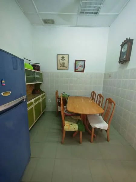 Kitchen features: blue refrigerator, wooden dining table, 4 wooden dining chairs, green cabinetry, white tiled backsplash, grey floor tiles, wall clock, framed artwork, microwave, kitchen counter, open shelving.