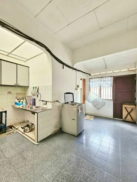 Kitchen features: white tiled walls, grey tiled flooring, single-bowl stainless-steel sink, built-in cabinets with white finish, countertop space, refrigerator, window with mesh screen, door leading outside, washing machine, open layout, overhead lighting.