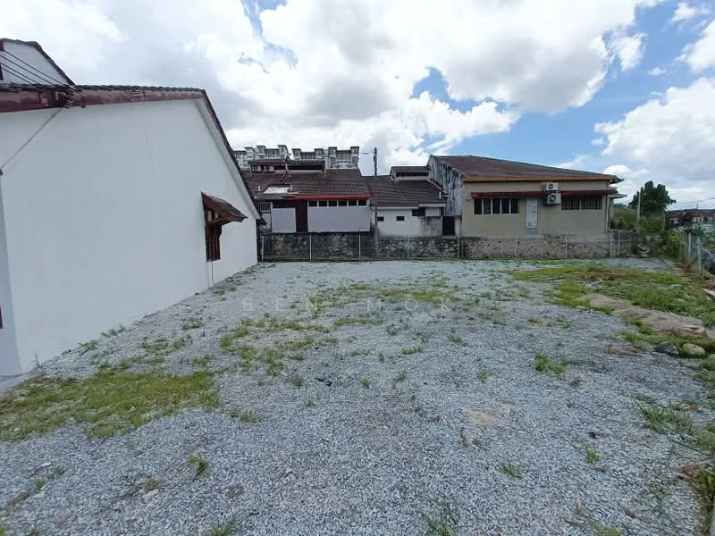 Exterior features: gravel ground, surrounding fence, adjacent buildings, cloudy sky, open space.