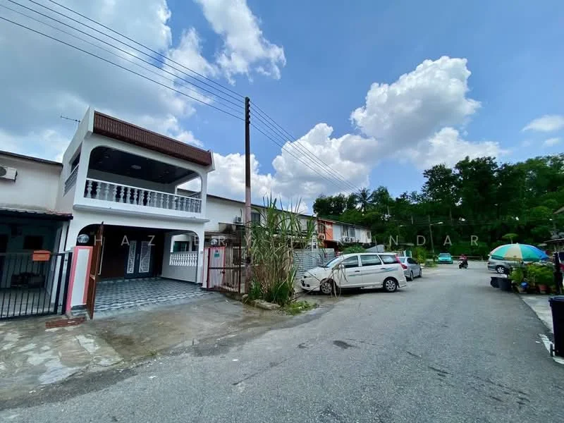 Exterior type: linked terrace house; features: two-storey house, white painted facade, red tiled roof, balcony with railing, paved driveway, manicured front garden, surrounded by greenery, visible parking area, street view, utility poles, cloudy sky; style: modern.