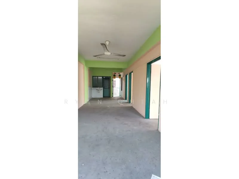 Room features: light green painted walls, cream painted walls, grey carpet flooring, ceiling fan, doorways with green frames, windows with green frames, kitchen area visible in the background, open layout.
