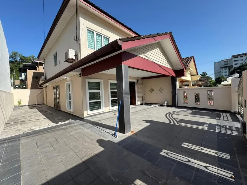 Exterior type: semi-detached house; features: two-storey building, red tiled roof, cream painted facade, large windows with green shutters, covered porch area, paved flooring, decorative wall panels, exposed concrete columns, surrounding fencing, outdoor space with sunlight; style: modern.
