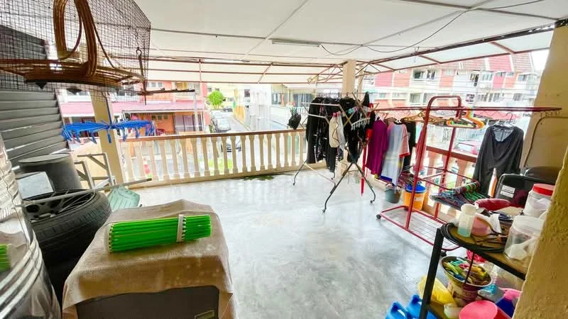 Room features: concrete flooring, covered balcony, clothes drying rack, hanging clothes, plastic storage containers, laundry items, metal railing, outdoor view, plastic bins, hanging birdcage.