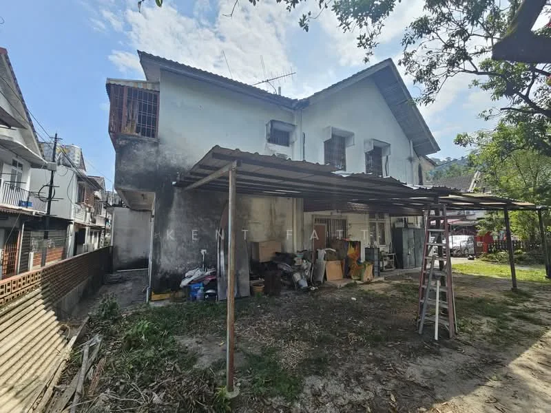 Exterior type: semi-detached house; features: white painted facade, flat roof, two-storey structure, exposed brick wall, metal awning, surrounding greenery, unmaintained garden area, storage items visible, ladder, outdoor space with dirt ground; style: traditional.