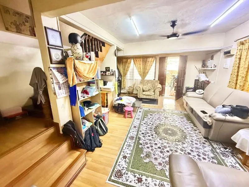 Living features: laminate flooring, cream painted walls, ceiling fan, sofa in beige, coffee table, area rug with floral pattern, curtains in yellow, bookshelf with various items, staircase leading to upper floor, decorative wall art, wall-mounted decor, light fixtures; style: traditional.