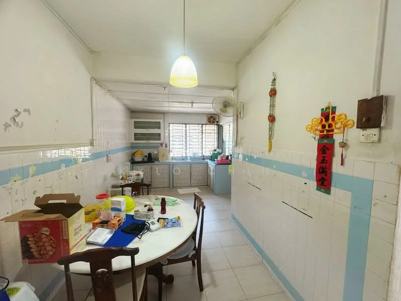 Kitchen features: white tiled walls, light blue accent strip on walls, ceramic tile flooring, round dining table, wooden dining chairs, overhead pendant light, wall-mounted air conditioning unit, kitchen cabinets, various kitchen appliances on countertop, decorative wall hangings.