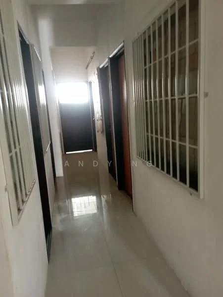 Hallway features: white painted walls, glossy tile flooring, metal security grilles on windows, wooden doors, natural light from end of hallway, light fixture on ceiling.