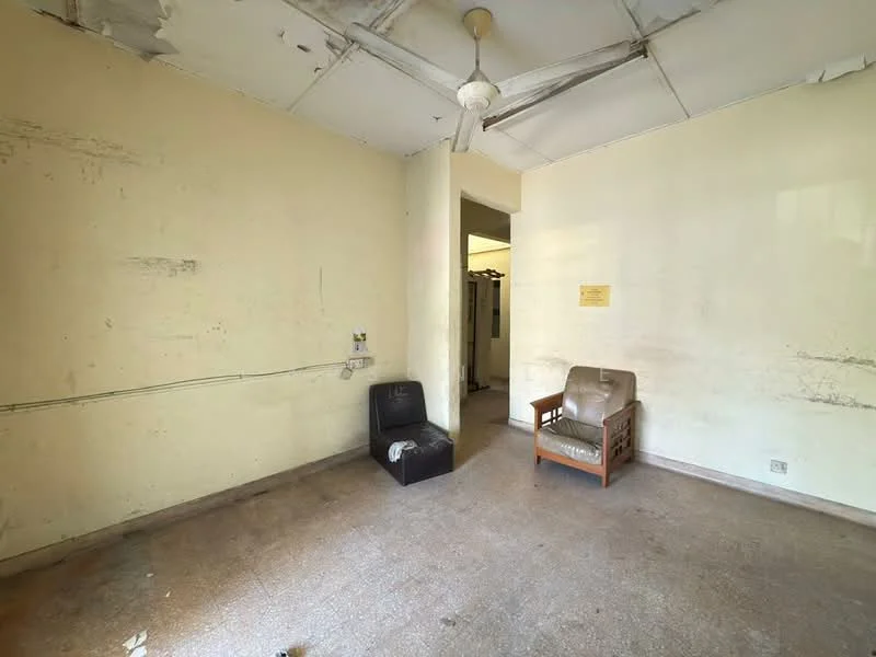 Room features: plain white walls, ceiling with visible wear, ceiling fan, two chairs, bare floor, exposed electrical wiring, no visible decor.