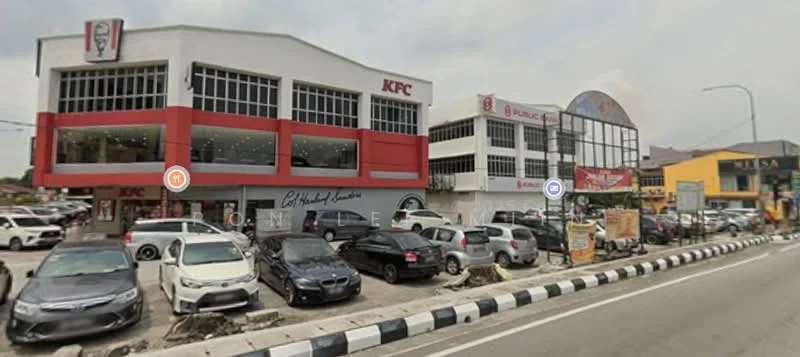 Exterior type: shophouse; features: red and white painted facade, glass windows, signage for KFC and Public Bank, multiple storeys, parking lot in front, street view, surrounded by vehicles, urban context; style: modern.