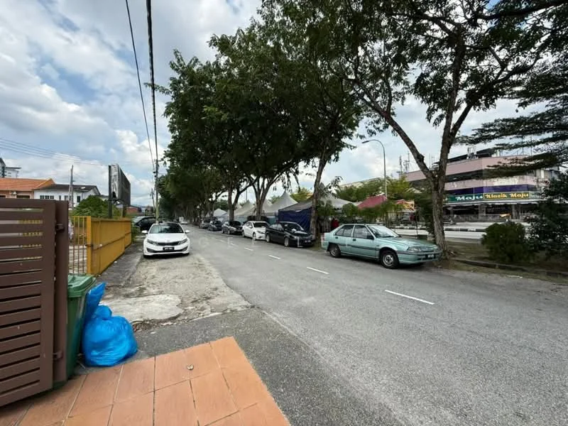 Exterior features: tree-lined street, paved road, parked cars, sidewalk, residential buildings in background, street lighting, curbside, visible signage on buildings.
