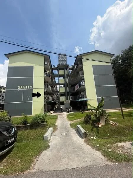 Exterior type: low-rise apartment block; features: green painted facade, grey accent panels, balconies with railings, multiple floors, walkway leading to entrance, surrounding greenery, visible laundry on balconies; style: modern.