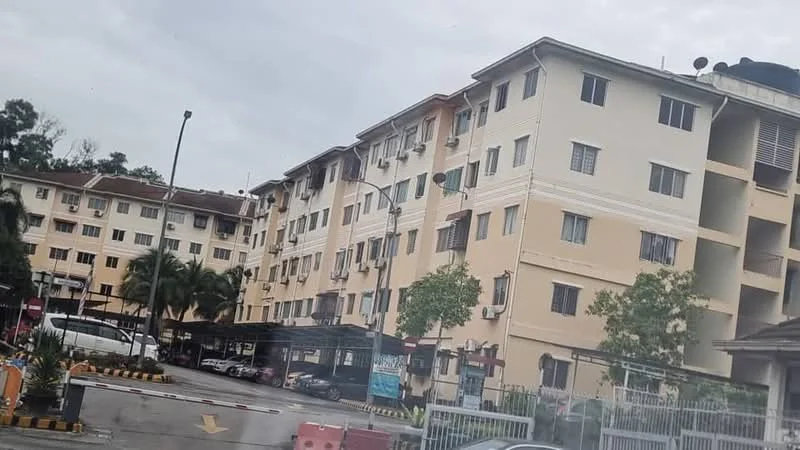 Exterior type: low-rise apartment block; features: cream painted facade, multiple storeys, balconies on upper floors, covered parking area, landscaped greenery, paved driveway, visible air conditioning units, security gate at entrance; style: modern.