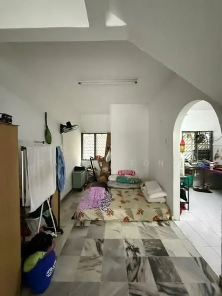 Room features: marble flooring, white painted walls, sloped ceiling, window with security bars, bed with bedding, stack of pillows, clothes drying rack, laundry basket, small refrigerator, table with items, various household items, open closet, light fixture on ceiling.
