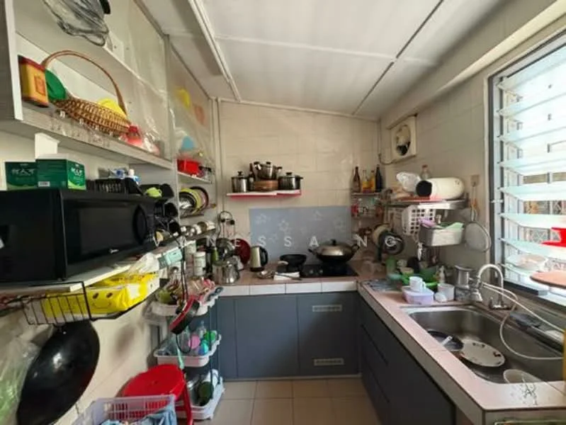 Kitchen features: grey cabinetry, stainless-steel sink, chrome pull-down faucet, ceramic tile flooring, wall-mounted shelves, various kitchen utensils, cooking pots and pans, microwave, stove with pots, window with louvered shutters, countertop with clutter, basket for storage.