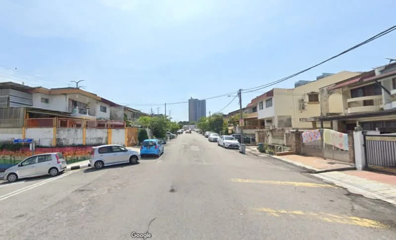 Exterior type: low-rise apartment block; features: residential street, multiple parked cars, sidewalks, power lines, surrounding greenery, mixed architectural styles, clear blue sky; style: contemporary.
