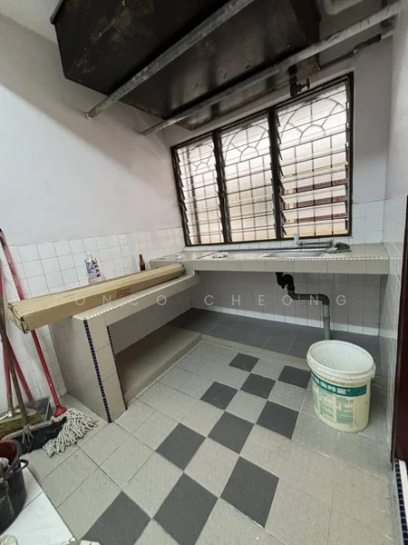 Kitchen features: single-bowl stainless-steel sink, chrome pull-down faucet, countertop with wooden surface, white tiled backsplash, grey and white checkered floor tiles, window with metal grille, built-in cabinetry, cleaning supplies visible.