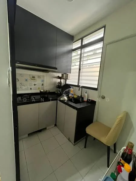Kitchen features: black upper cabinets, grey lower cabinets, white tiled backsplash, stainless-steel sink, chrome faucet, built-in stove, countertop with space for appliances, window for natural light, white tiled flooring, small dining chair; style: modern.