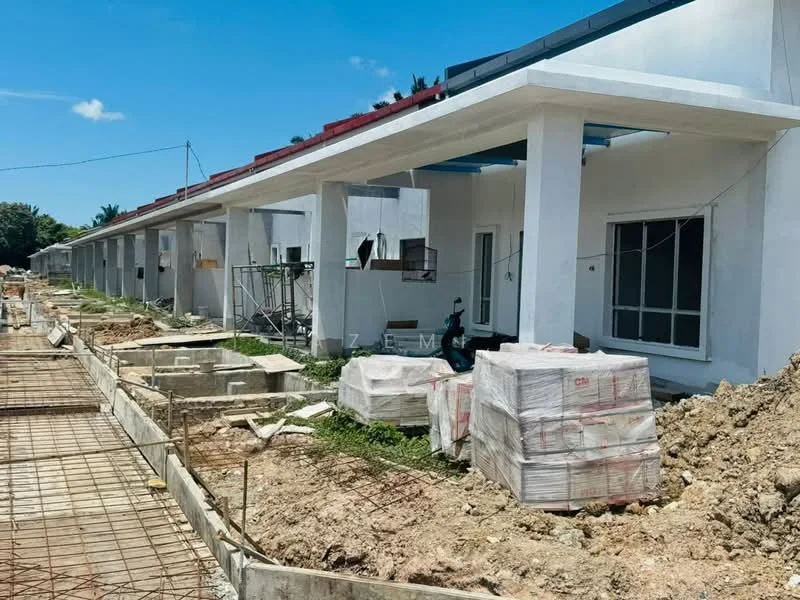 Exterior type: linked terrace house; features: white painted facade, flat roof, construction materials visible, unfinished landscaping, exposed foundation work, scaffolding present, windows with frames, concrete pathways, surrounding greenery; style: modern.