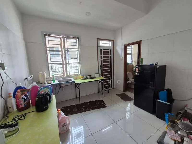 Kitchen features: white tiled walls, glossy white floor tiles, green countertop, single-bowl stainless-steel sink, chrome pull-down faucet, black refrigerator, microwave, kettle, plastic storage containers, dining table, plastic chair, window with metal grille, door with metal grille, area rug.