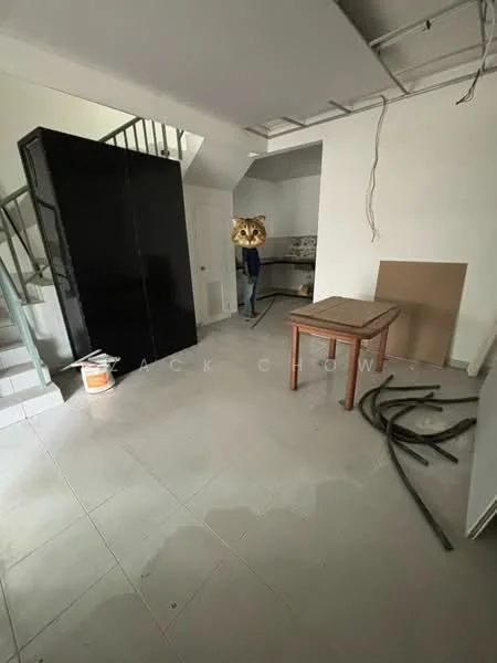Room features: black refrigerator, table, staircase, tile flooring, unfinished walls, exposed ceiling, plumbing pipes on floor, kitchen area in background.