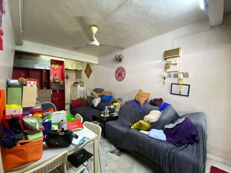 Living features: grey fabric sofa, 2-seater sofa, ceiling fan, marble tile flooring, wall-mounted air conditioning unit, decorative wall art, various cushions and throws, coffee table, multiple bags and boxes on the floor, wall with electrical outlets, light fixture on ceiling.