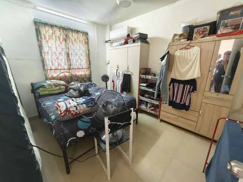 Bedroom features: single bed with blue and white bedding, wooden wardrobe with sliding doors, white painted walls, tile flooring, curtains with floral pattern, ceiling fan, small desk with chair, open shelving unit, wall-mounted mirror, clothes hanging on hooks.