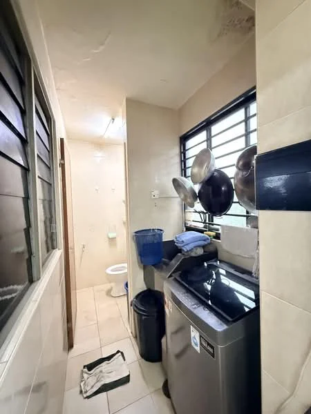 Laundry features: front-load washing machine, black countertop, white tiled flooring, cream painted walls, window with metal grills, toilet, hanging pots, waste bin, cleaning cloth, blue laundry basket.