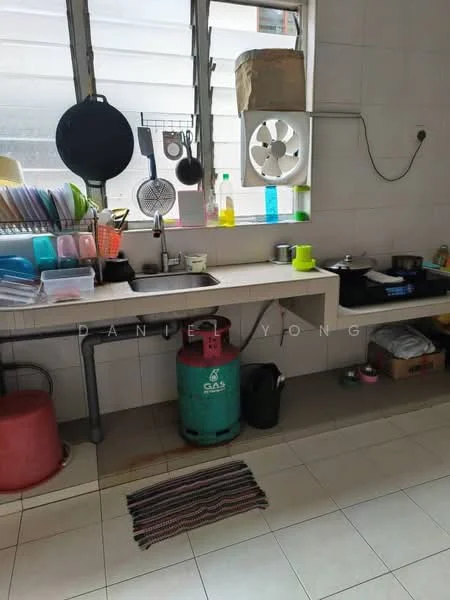 Kitchen features: single-bowl stainless-steel sink, chrome pull-down faucet, white tiled walls, light-colored countertop, gas cylinder, kitchen utensils, various colored plastic containers, hanging pot rack, window with metal grilles, floor tiles, striped area rug.